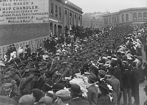 Crowds watching a procession of soldiers marching down Dunedin