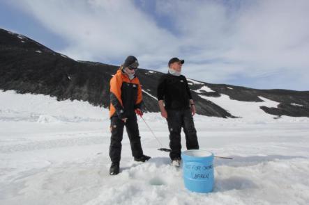 Kathryn Ryan ice fishing in front of Arrival Heights with Clive Evans